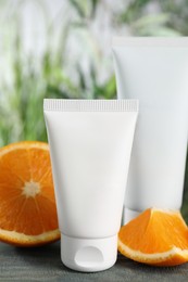 Photo of Tubes of hand cream and orange on light blue wooden table