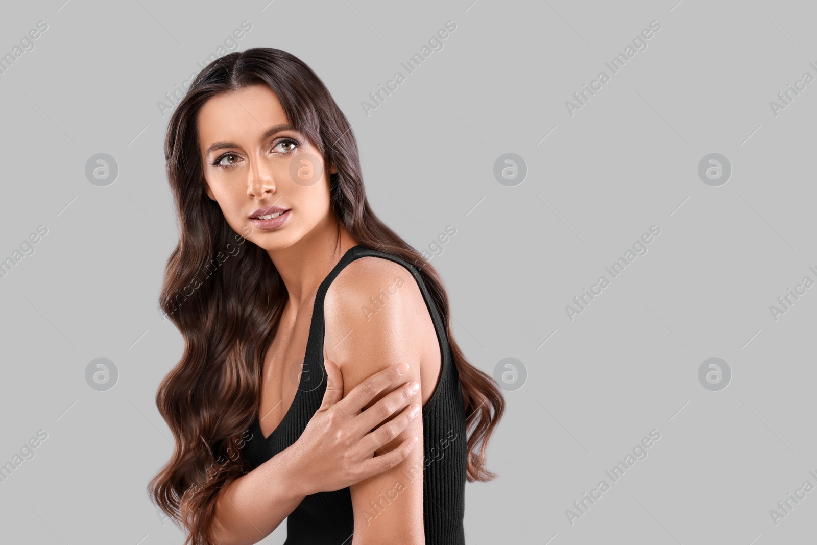 Photo of Hair styling. Beautiful woman with wavy long hair on grey background, space for text