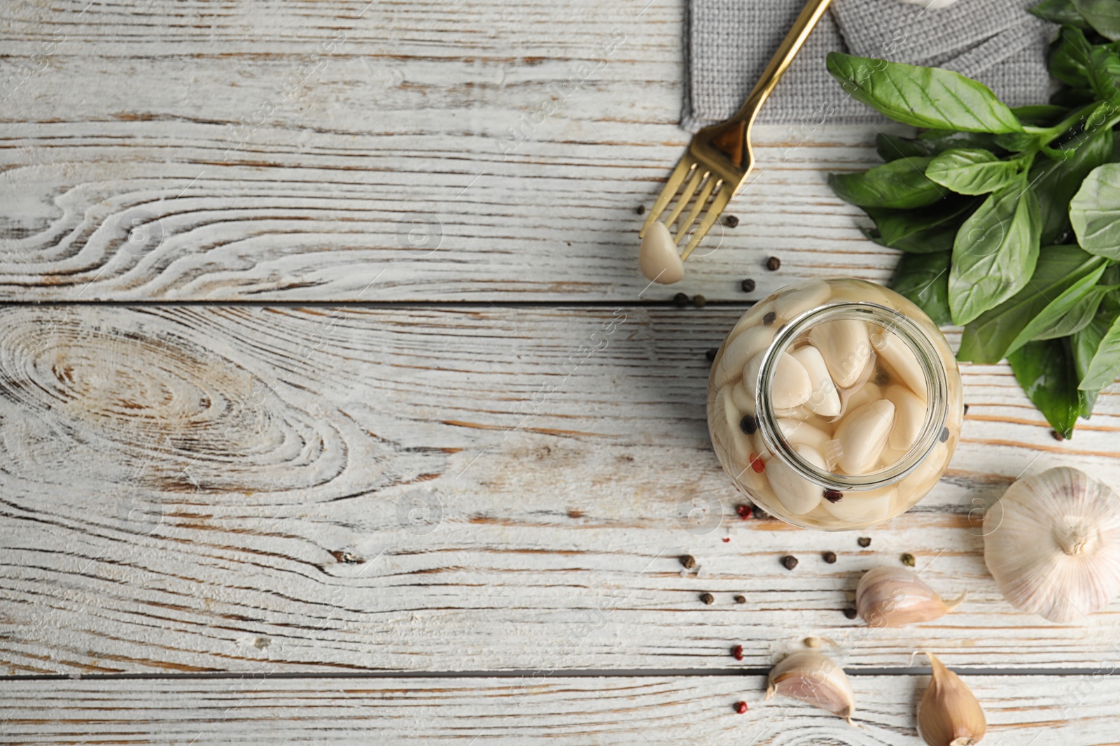 Photo of Flat lay composition with jar of pickled garlic on white wooden table. Space for text