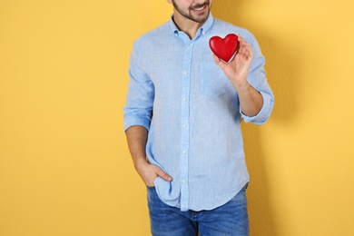 Photo of Man holding decorative heart on color background, closeup