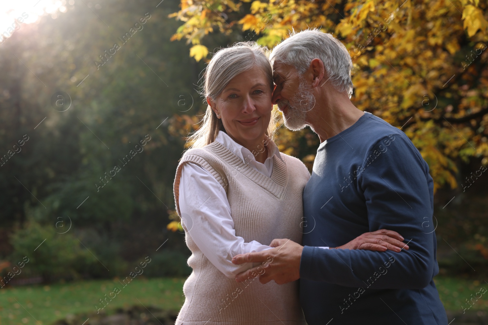 Photo of Portrait of affectionate senior couple in autumn park, space for text