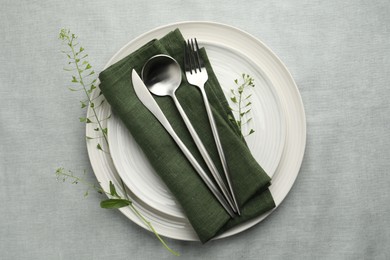 Photo of Stylish setting with cutlery, leaves and plates on grey table, top view