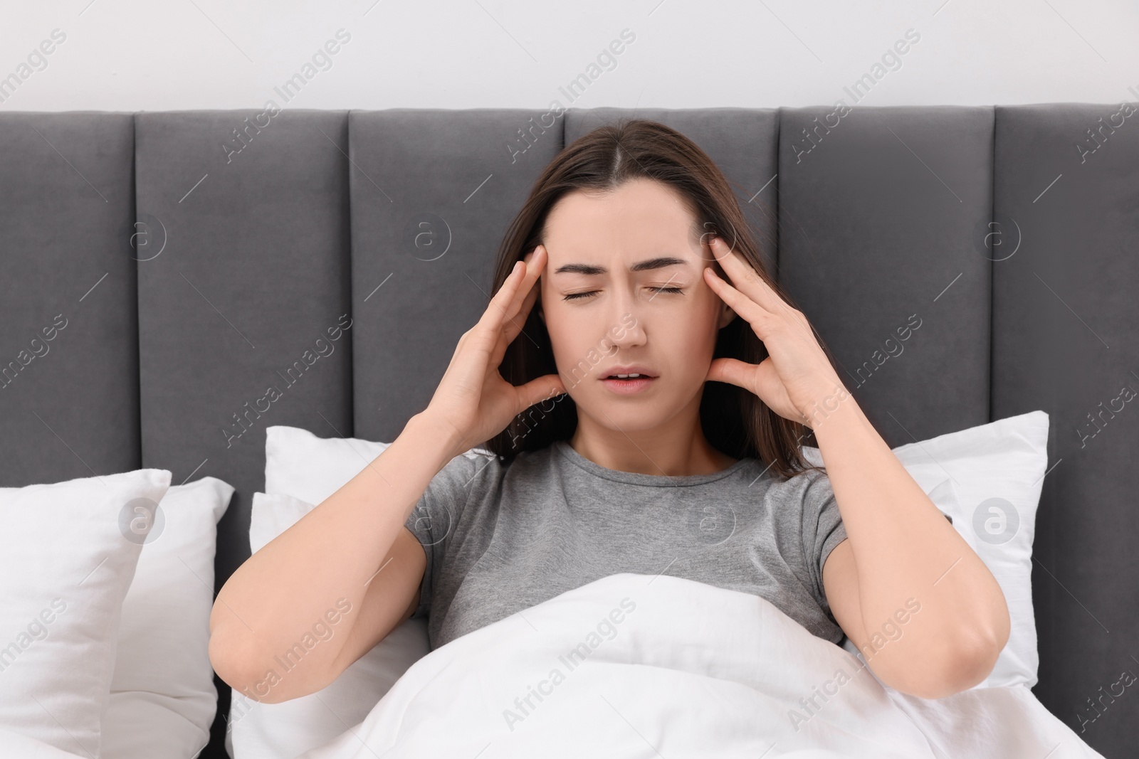 Photo of Sad woman suffering from headache in bed indoors