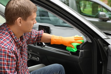 Photo of Man washing car door with rag outdoors