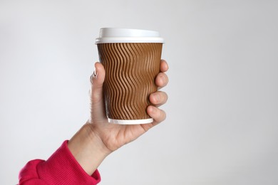 Woman holding takeaway paper coffee cup on white background, closeup