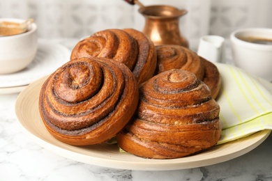 Photo of Plate with baked cinnamon rolls on table