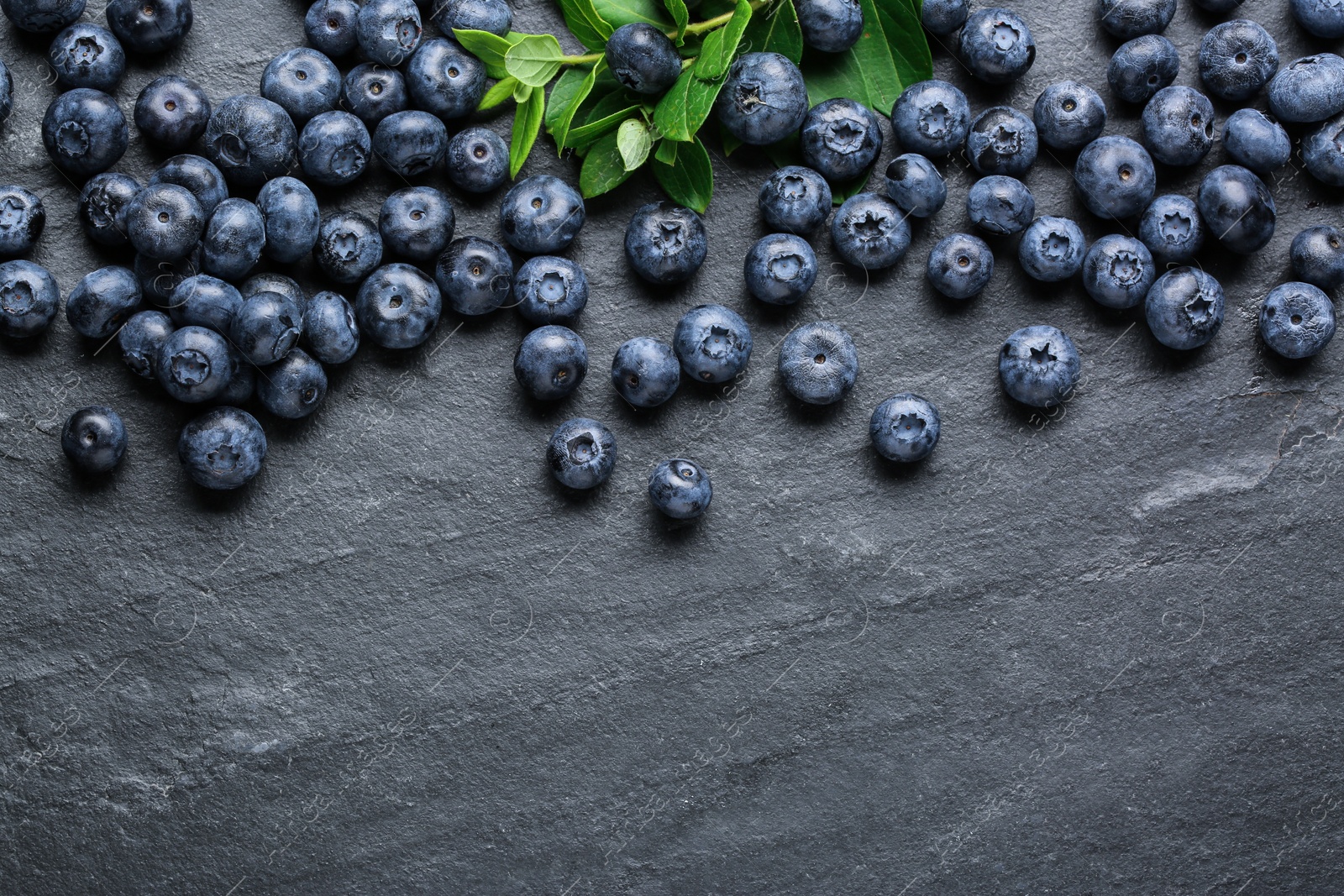 Photo of Tasty fresh blueberries on grey table, flat lay. Space for text