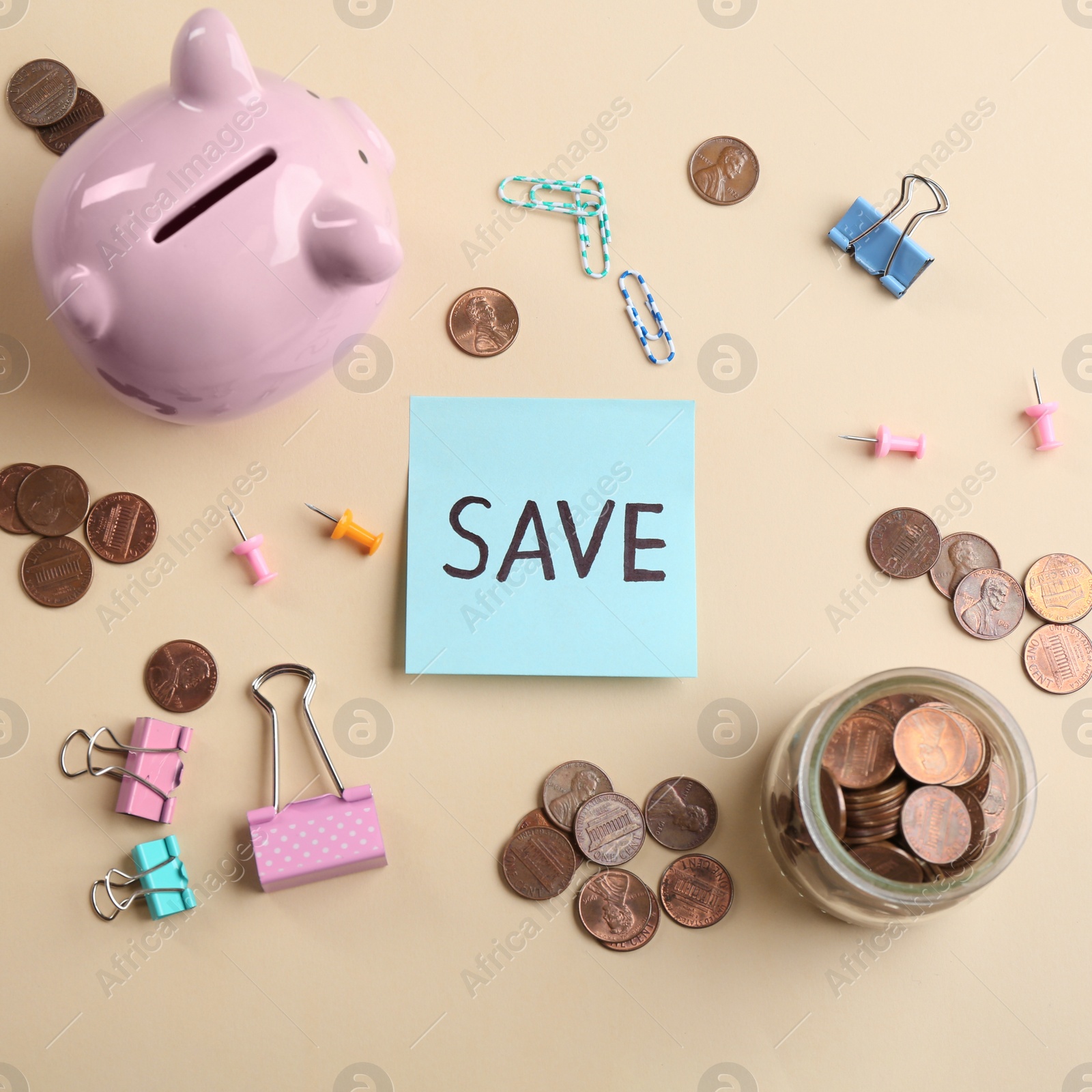 Photo of Note with word SAVE, piggy bank and coins on beige background, flat lay