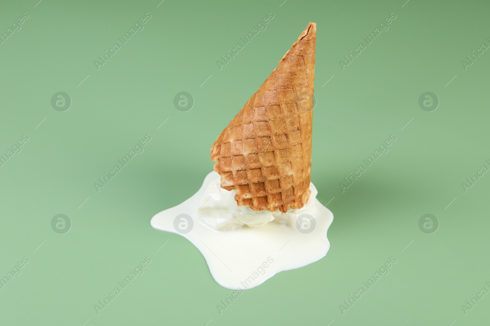 Photo of Melted ice cream and wafer cone on green background