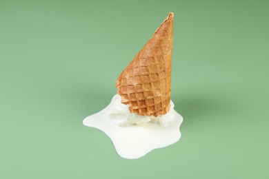 Photo of Melted ice cream and wafer cone on green background