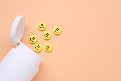 Photo of Bottle and yellow antidepressant pills with happy faces on pale orange background, flat lay. Space for text