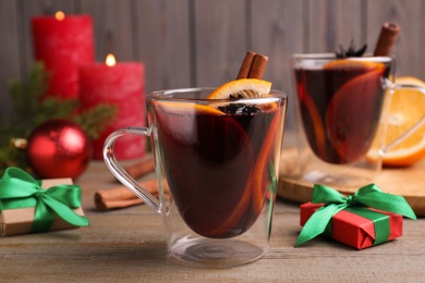 Glass cups of aromatic mulled wine on wooden table