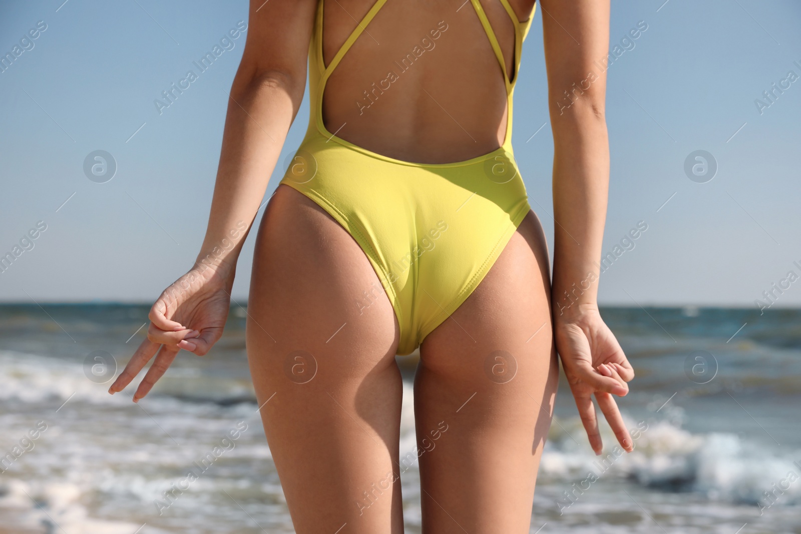 Photo of Attractive young woman with perfect body on beach, closeup. Back view