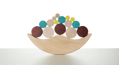 Photo of Wooden balance toy on light grey table against white background. Children's development