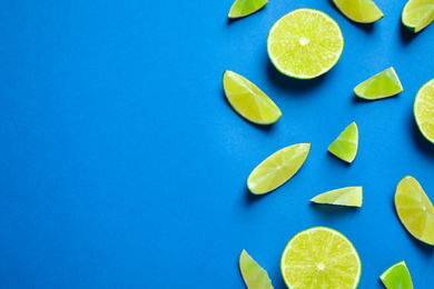 Photo of Juicy fresh lime slices on blue background, flat lay. Space for text