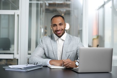 Photo of Happy man working at table in office. Lawyer, businessman, accountant or manager