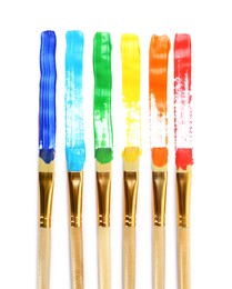 Photo of Brushes with colorful paints and strokes on white background, top view