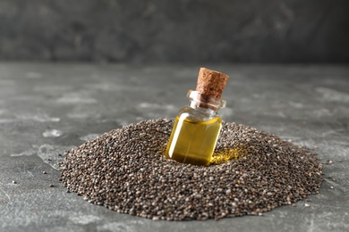 Photo of Bottle of chia oil in seeds on table