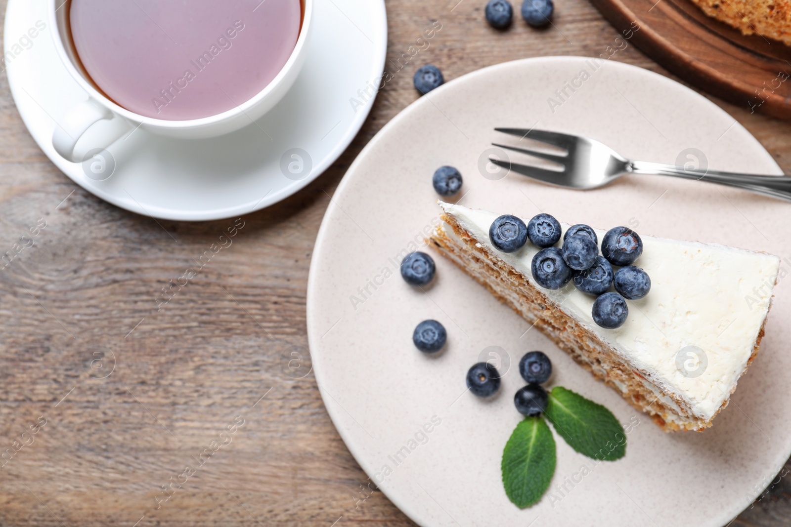 Photo of Tasty cake with berries and tea on wooden table, flat lay