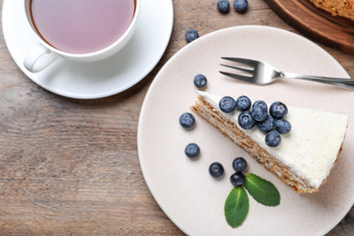 Tasty cake with berries and tea on wooden table, flat lay