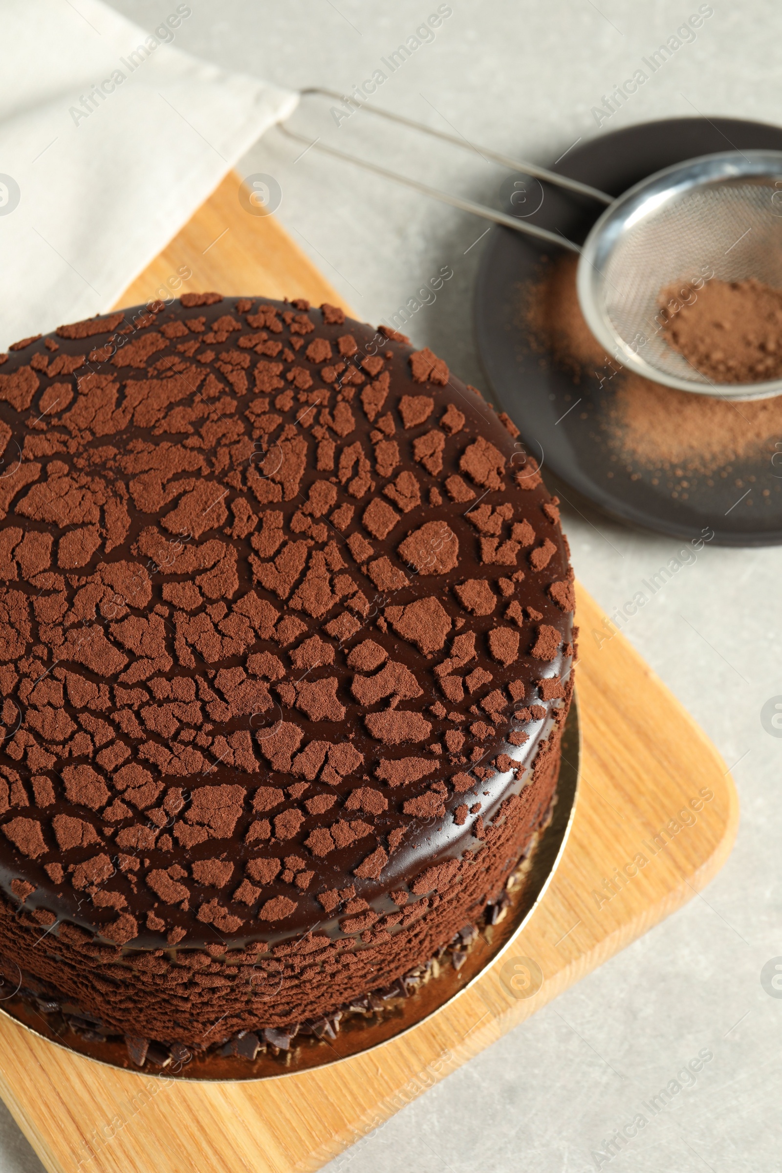 Photo of Delicious chocolate truffle cake and cocoa powder on light grey table, above view