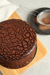 Photo of Delicious chocolate truffle cake and cocoa powder on light grey table, above view