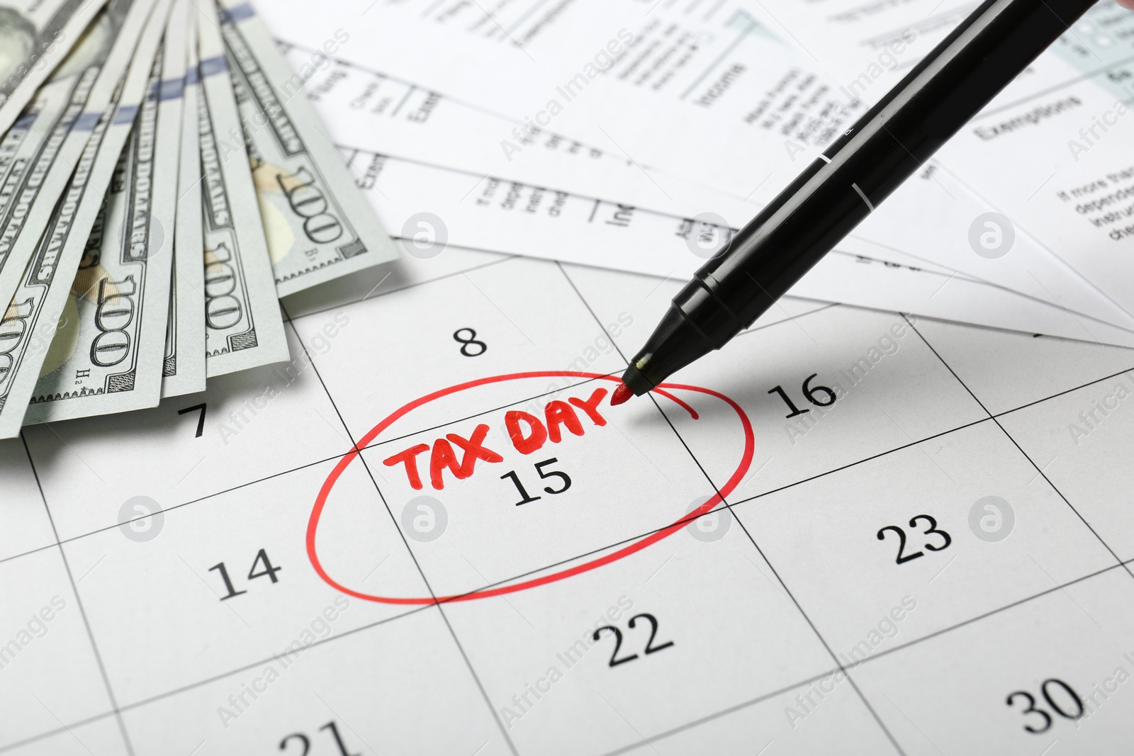 Photo of Marking tax day in calendar, felt pen, documents and money, closeup