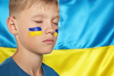 Little boy near Ukrainian flag, closeup. No war concept