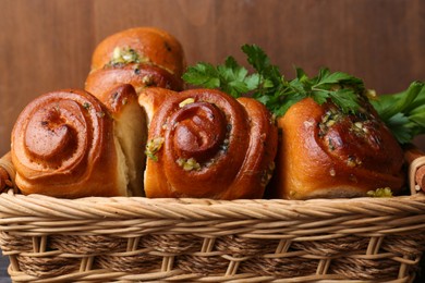 Photo of Delicious pampushky (buns with garlic) in wicker basket, closeup