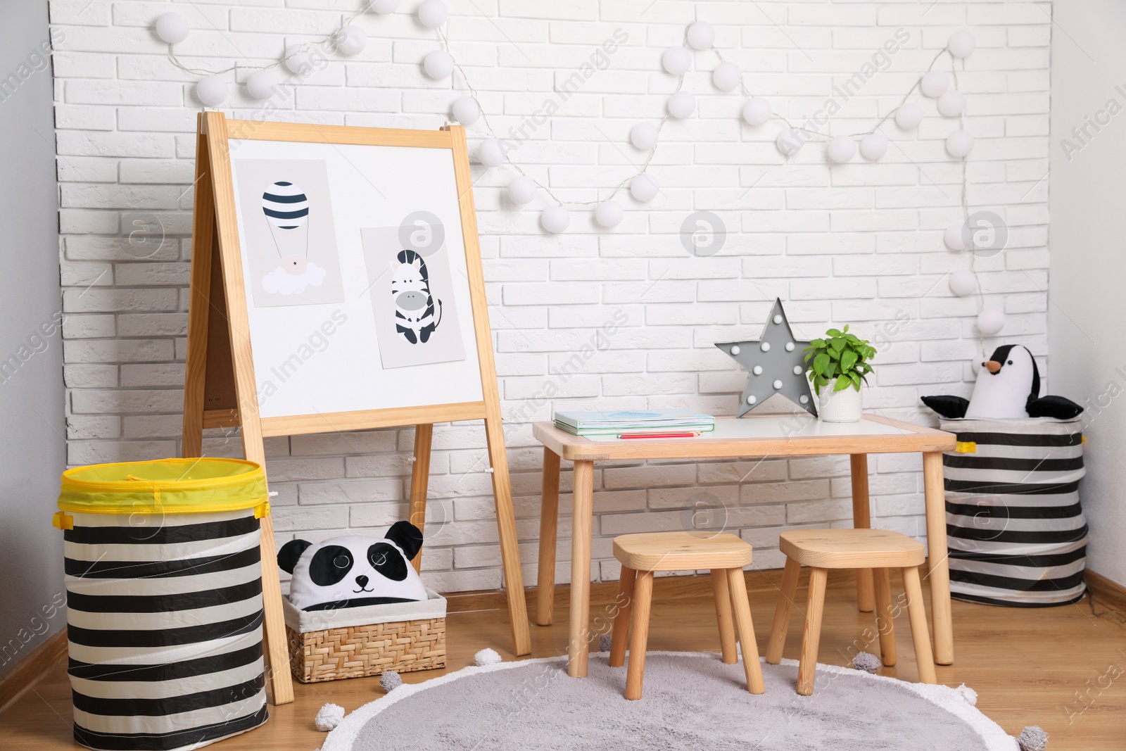 Photo of Stylish child room interior with wooden table and board near white brick wall