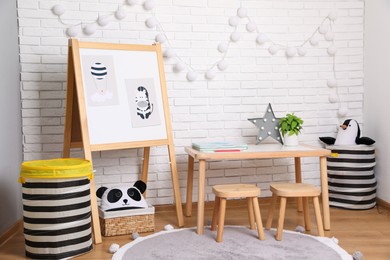 Photo of Stylish child room interior with wooden table and board near white brick wall