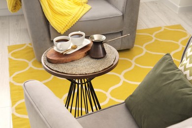 Photo of Cups of coffee and cezve on table in living room