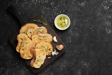 Tasty baguette with garlic served on grey textured table, flat lay. Space for text