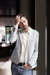 Attractive serious man wearing jacket in hall