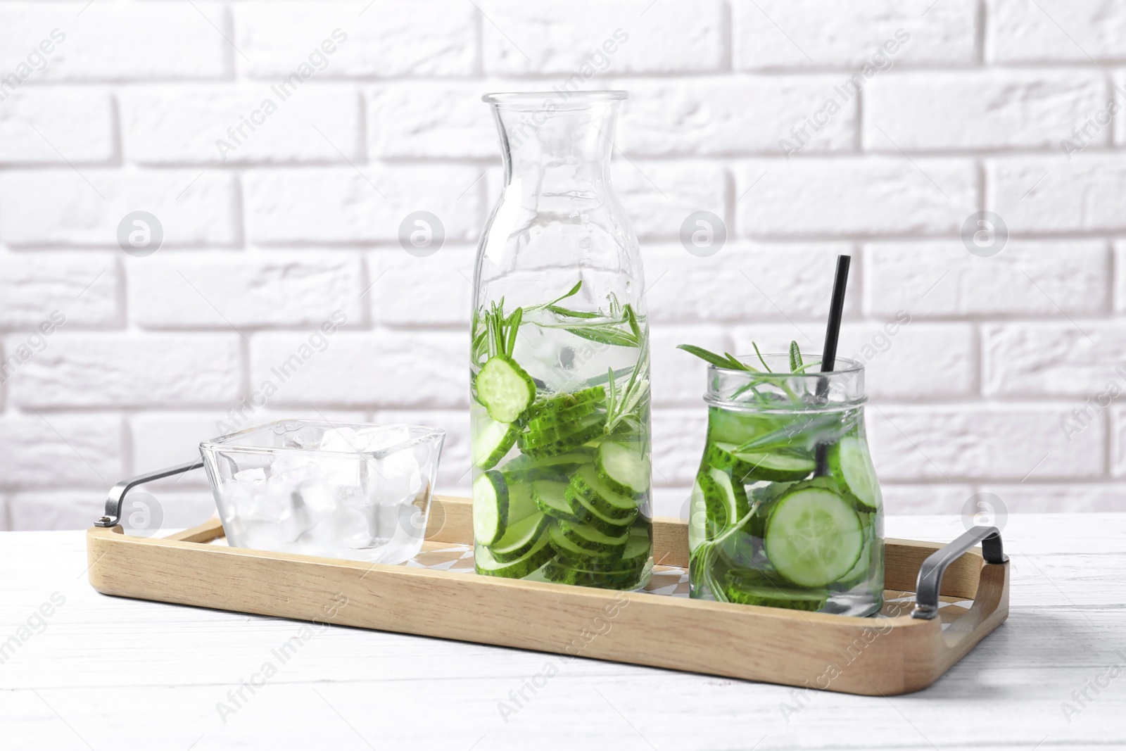 Photo of Natural lemonade with cucumber and rosemary in glassware on table