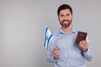 Photo of Immigration. Happy man with passport and flag of Israel on gray background, space for text