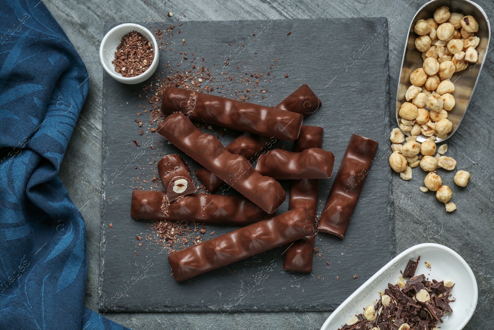 Photo of Tasty chocolate bars with nuts on black table, flat lay