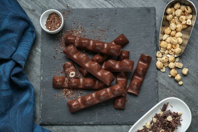 Photo of Tasty chocolate bars with nuts on black table, flat lay