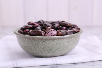 Photo of Bowl with dry kidney beans on table, closeup