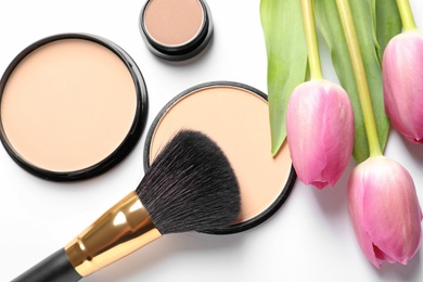 Makeup products and spring flowers on white background, top view