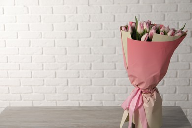 Photo of Beautiful bouquet of fresh pink tulips on light wooden table. Space for text