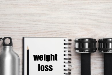 Photo of Weight loss concept. Flat lay composition with notebook, dumbbells and bottle of water on white wooden table, space for text