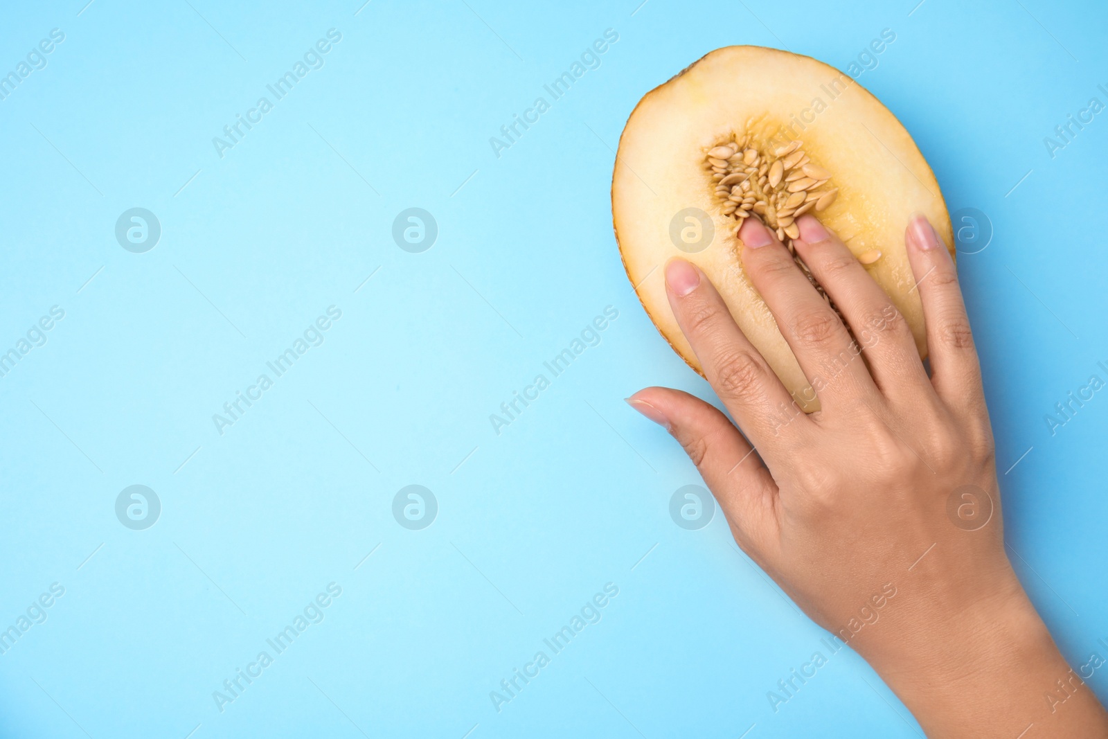 Photo of Young woman touching half of melon on blue background, top view with space for text. Sex concept