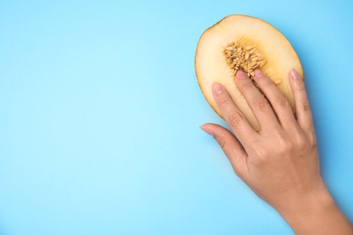 Young woman touching half of melon on blue background, top view with space for text. Sex concept