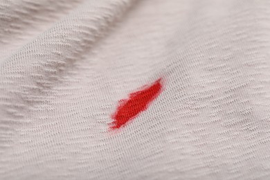 Photo of Stain of red ink on beige shirt, closeup