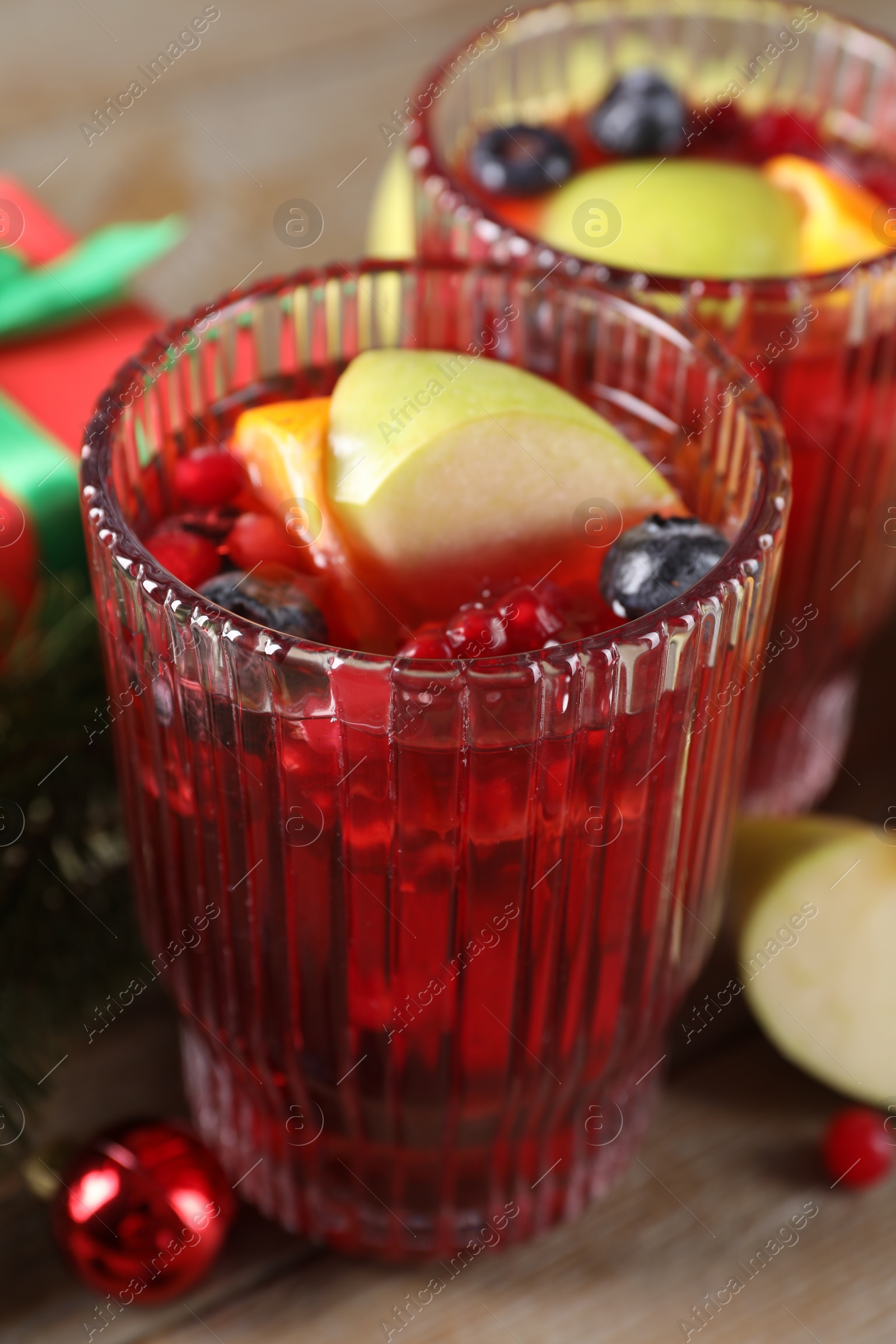 Photo of Aromatic Christmas Sangria drink in glasses on table, closeup