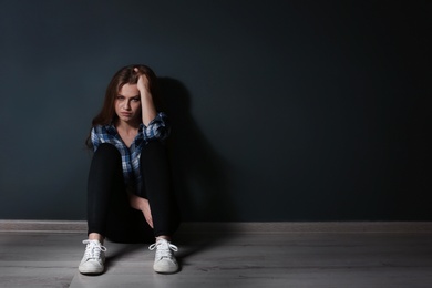 Photo of Depressed young woman sitting on floor in darkness