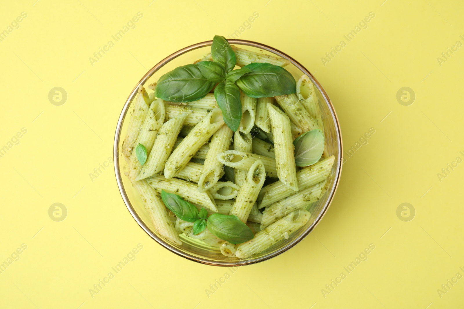 Delicious pasta with pesto sauce and basil on yellow background, top view Photo of Delicious pasta with pesto sauce and basil on yellow background, top view