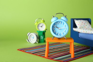 Photo of Alarm clock as winner on stool near losing competitors against green background, space for text. Competition concept