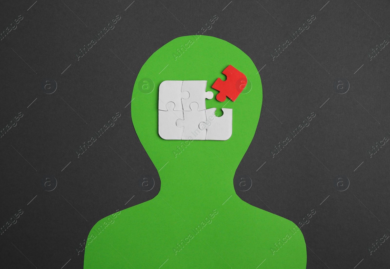 Photo of Human paper cutout with jigsaw puzzles in head, red piece as solution idea on black background, flat lay
